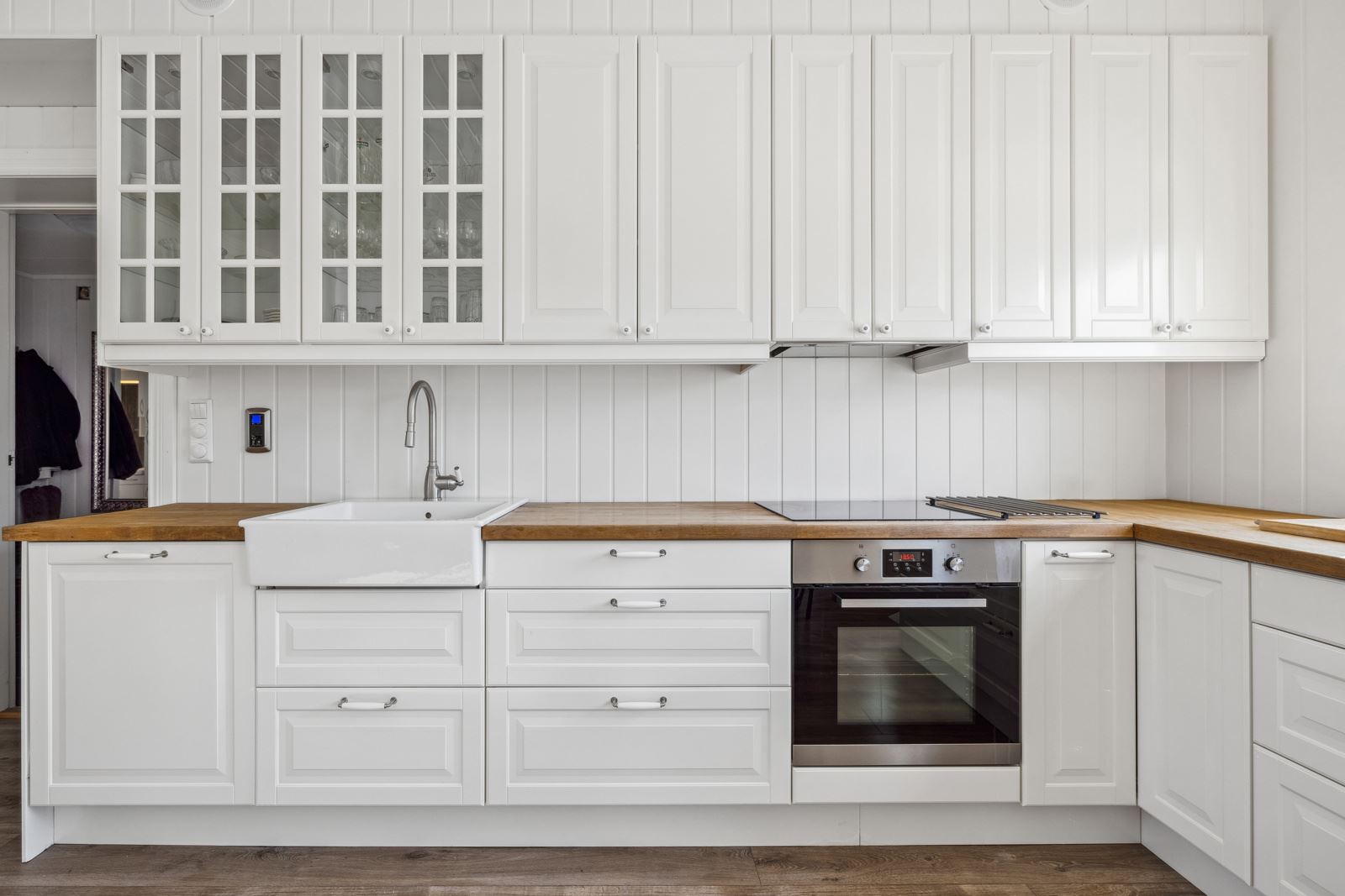 Kjøkkenet har hvite, profilerte fronter, benkeplate i heltre og vaskekum i porselen.