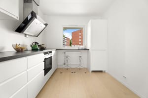Kjøkkeninnredning med glatte fronter. Laminat benkeplate med nedfelt vaskekum og belysning over benkeplaten