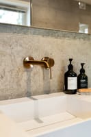 Badet har eksklusive materialvalg med kalkstein, kobberfargede armaturer og oppbevaringsplass i innebygd speilskap