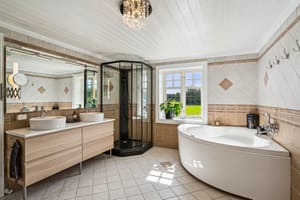 Badet i våningshuset er fra 2005, flislagt og familievennlig innredet med dusjkabinett, hjørnebadekar og dobbelservant.