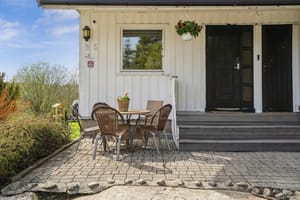 Kårboligen ligger nord på tunet, omkranset av hage og en steinsatt uteplass ved inngangen.