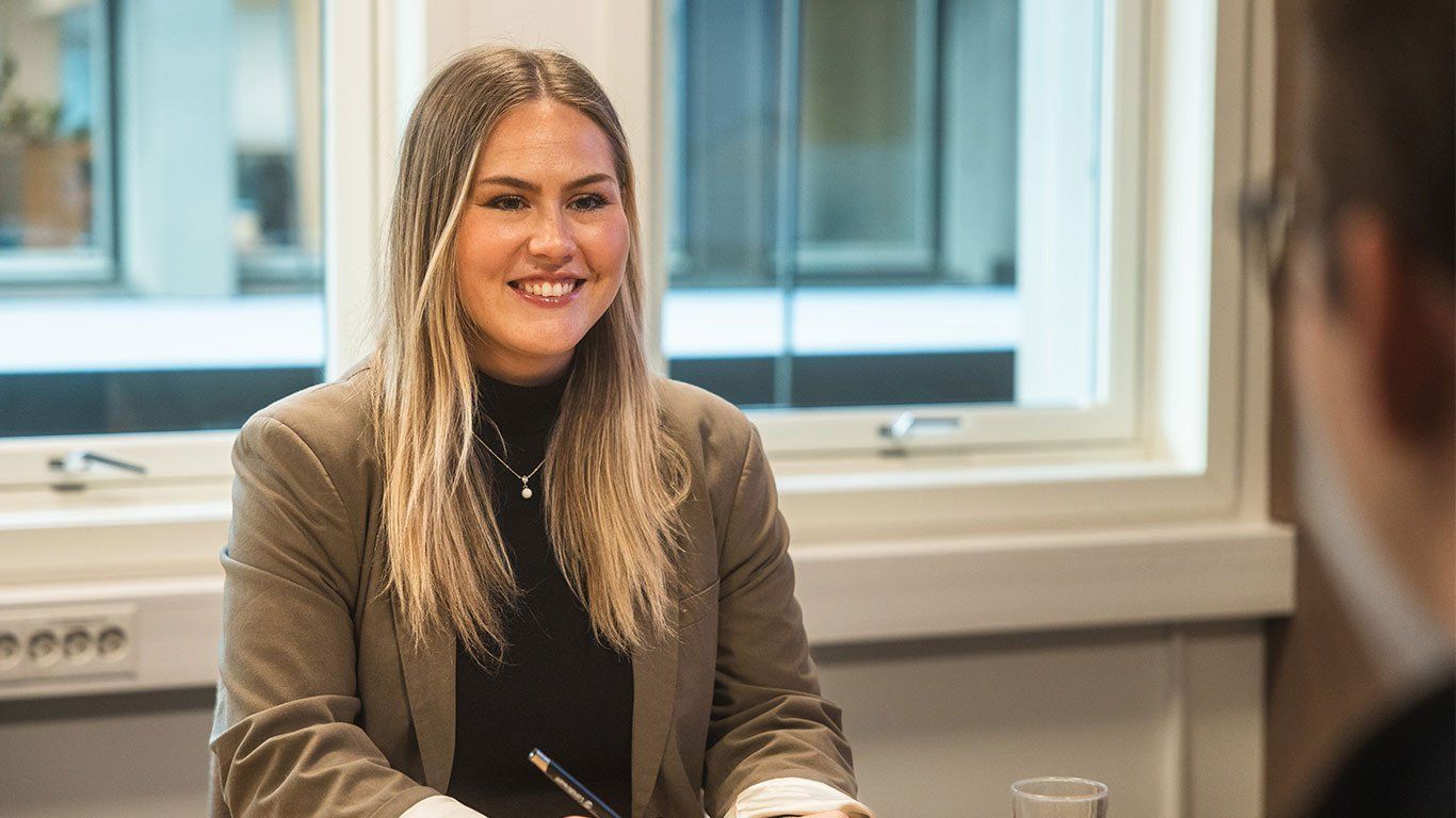 Kvinne på kontor, smiler til kollega