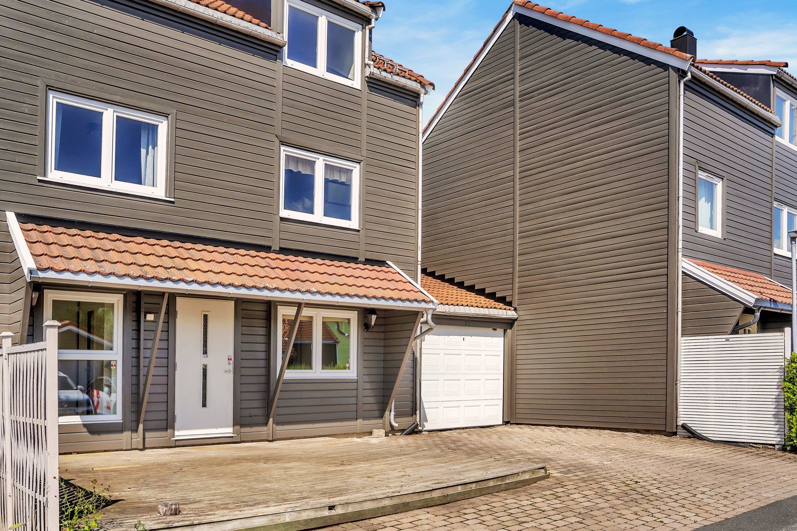 Boligen har et pent inngangsparti med platting og gårdsplass samt parkering i egen garasje