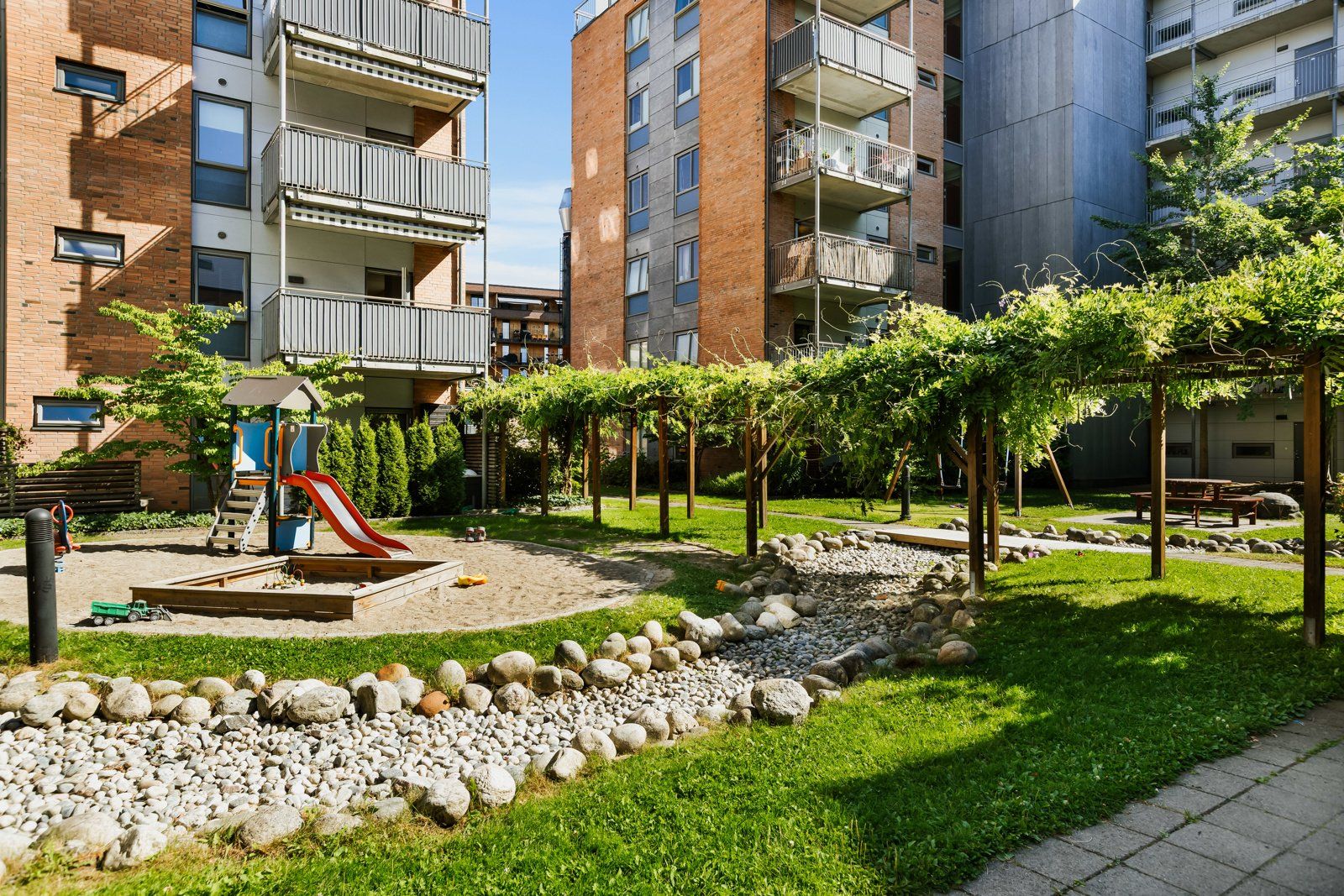 Området er pent opparbeidet med gressplen, beplantning, asfalterte veier/plasser og lekeplasser
