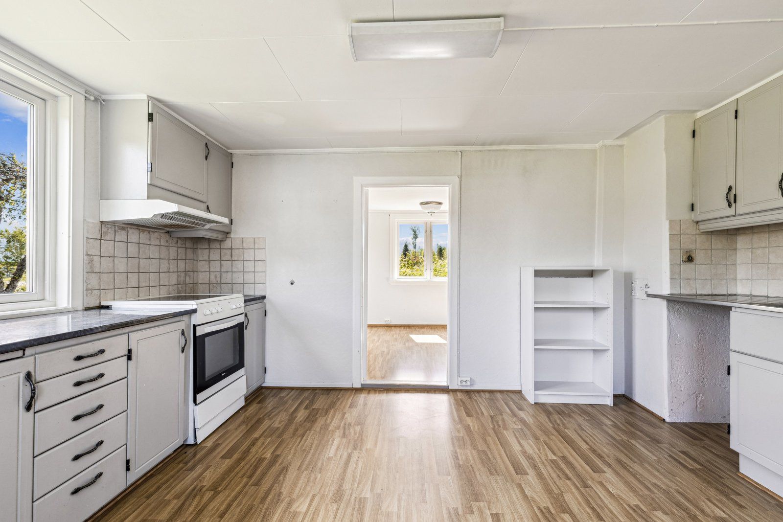 Kjøkkenet har ventilator over komfyrplassen, fliser over benken og opplegg for oppvaskmaskin.