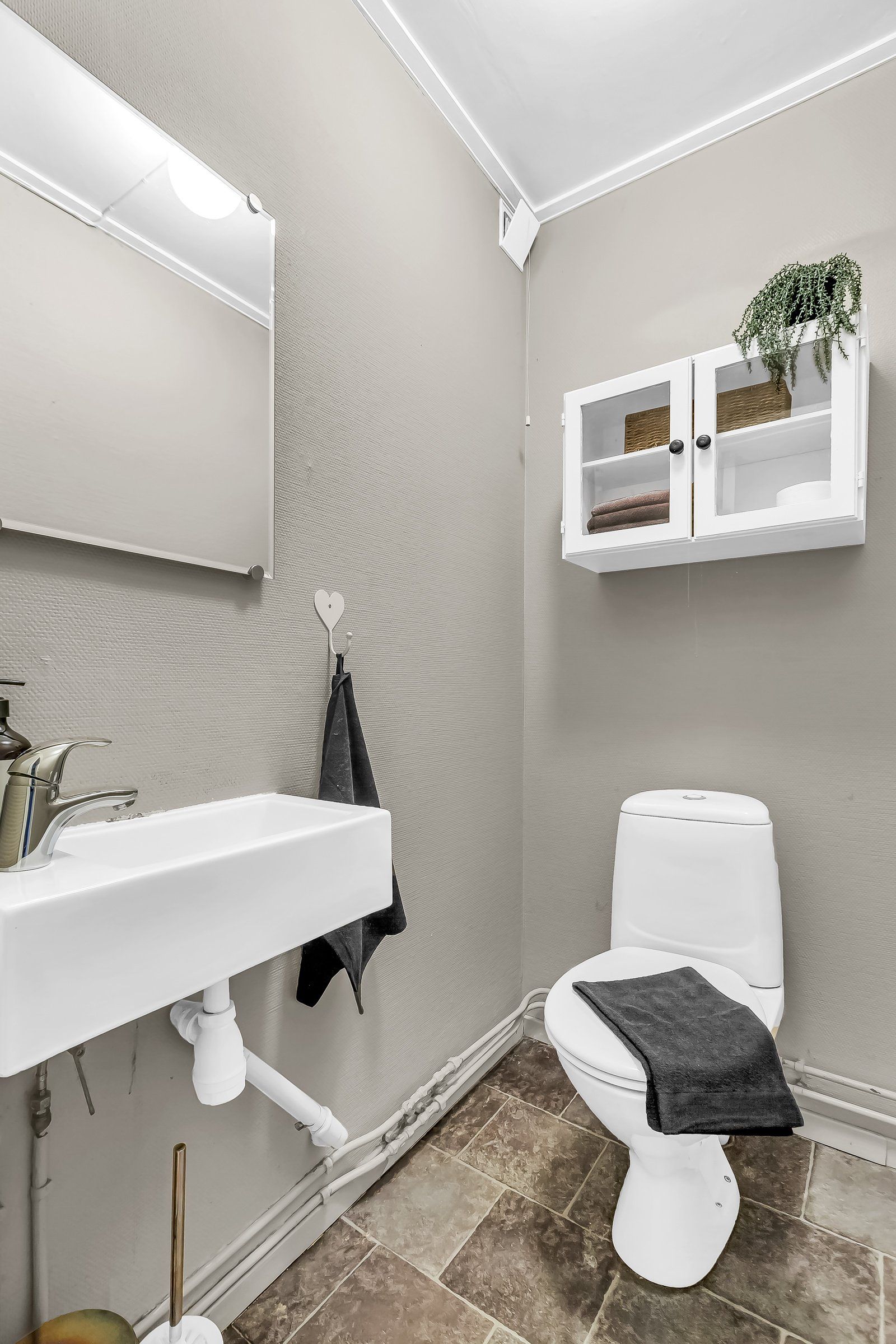 Vegg-i-vegg med badet er det et separat wc-rom med toalett, servant og speil 