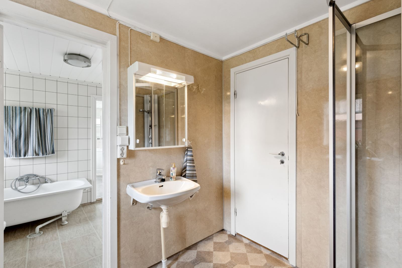 Badet i 1. etasje er et todelt rom, og har både badekar, dusj, wc og servant.