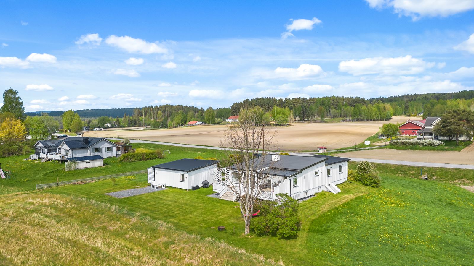 Eiendommen byr på en romslig og pent opparbeidet tomt, der blomsterbed, plen og trær som danner en harmonisk ramme rundt huset