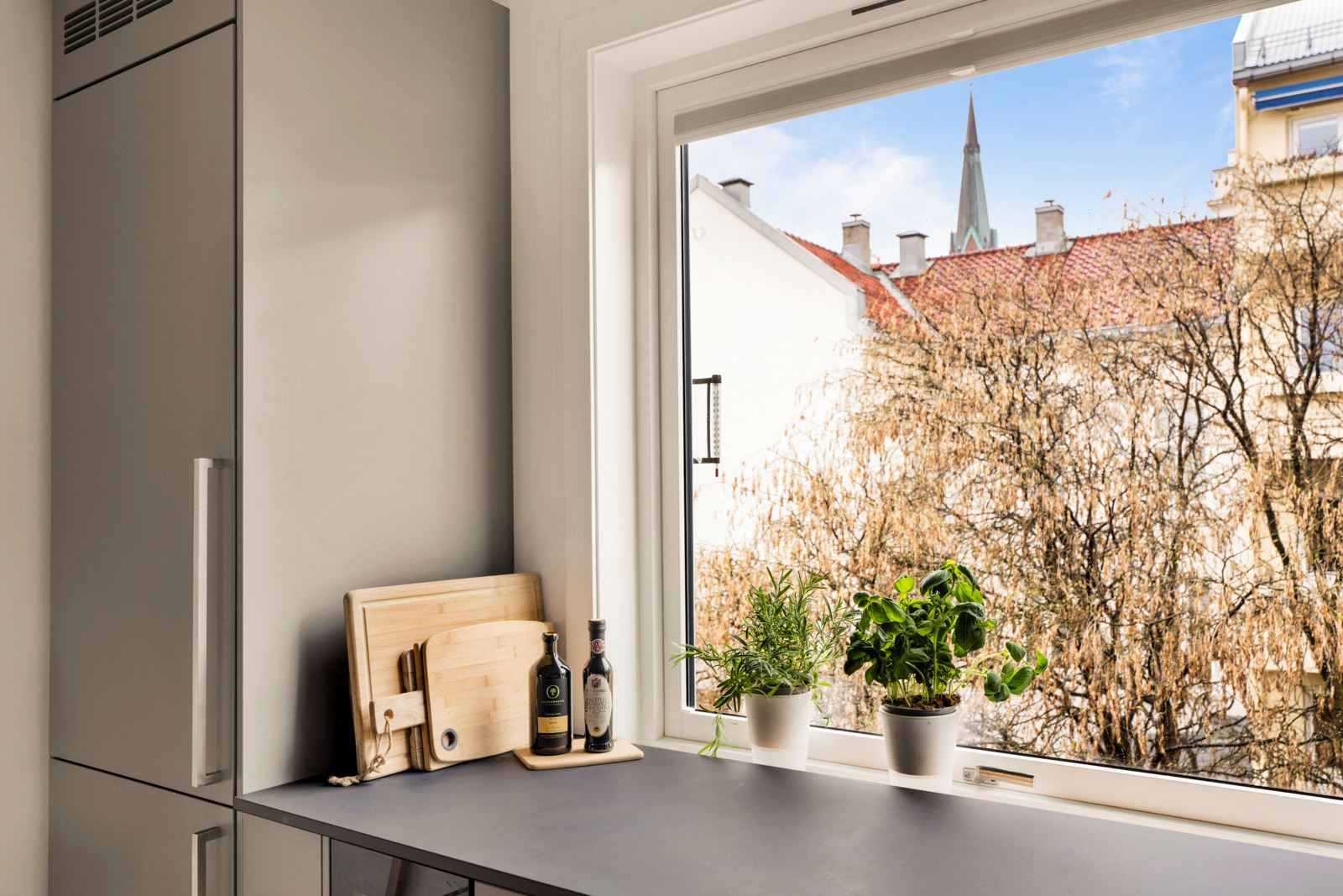 Kjøkkenet har barløsning og vakkert utsyn mot bakgård som er pent opparbeidet med grønn beplantning