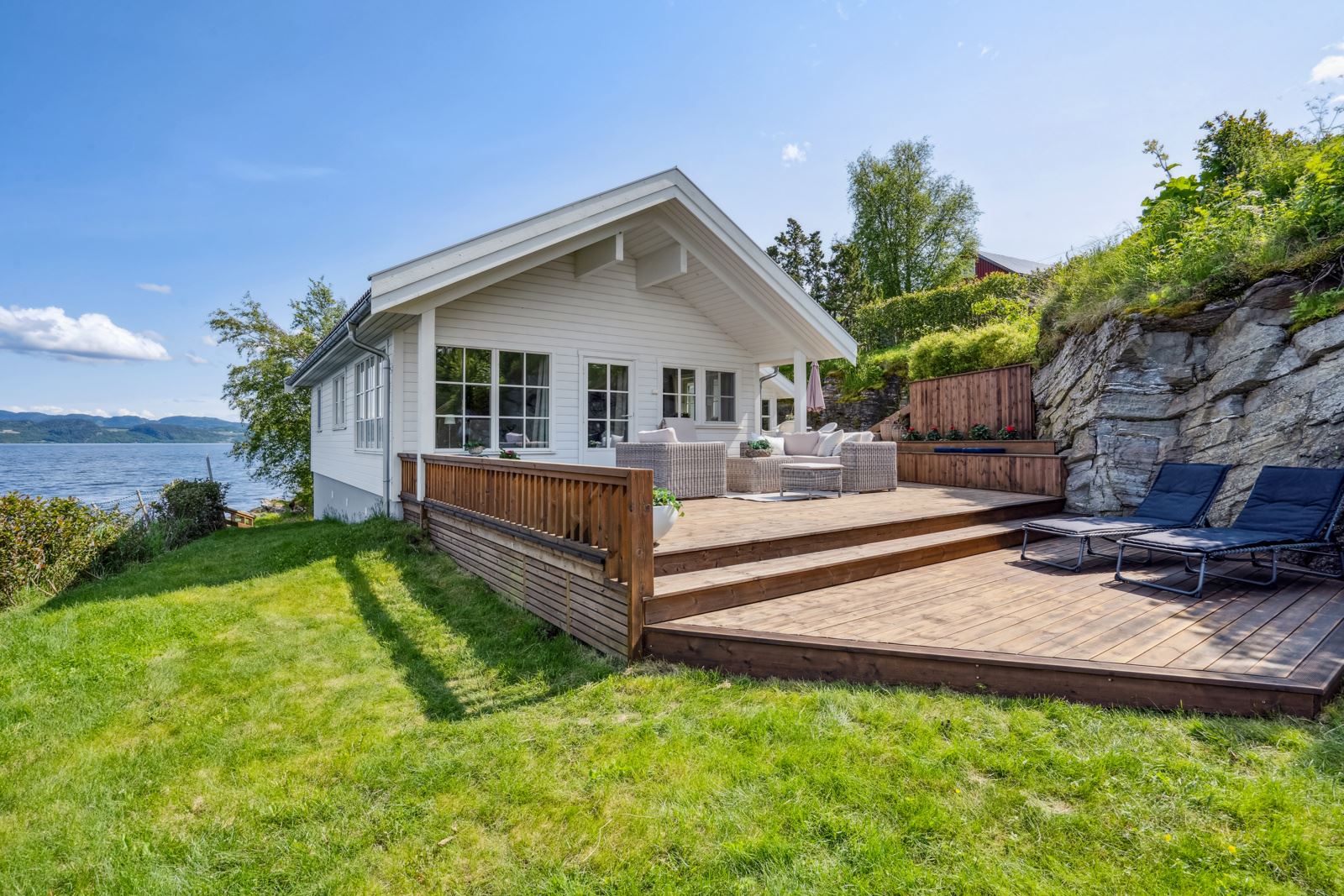 Pent opparbeidet uteareal med terrasser, plen og trapp ned fra parkeringen