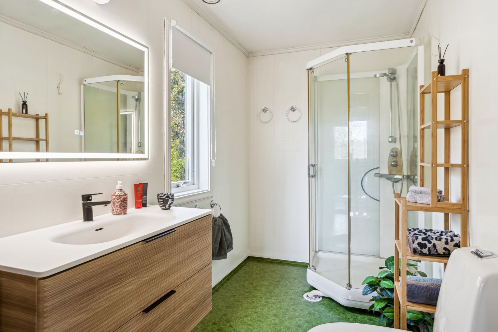 Badet i første etasje i kårboligen har nyere baderomsinnredning i moderne design, samt toalett og dusjkabinett.