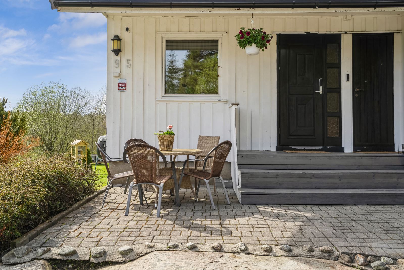 Kårboligen ligger nord på tunet, omkranset av hage og en steinsatt uteplass ved inngangen.