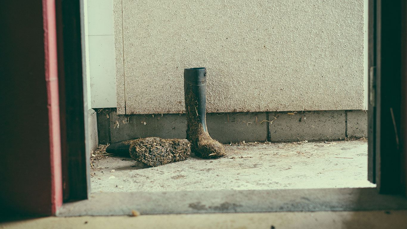 Møkkete gummistøvler står utenfor en dør